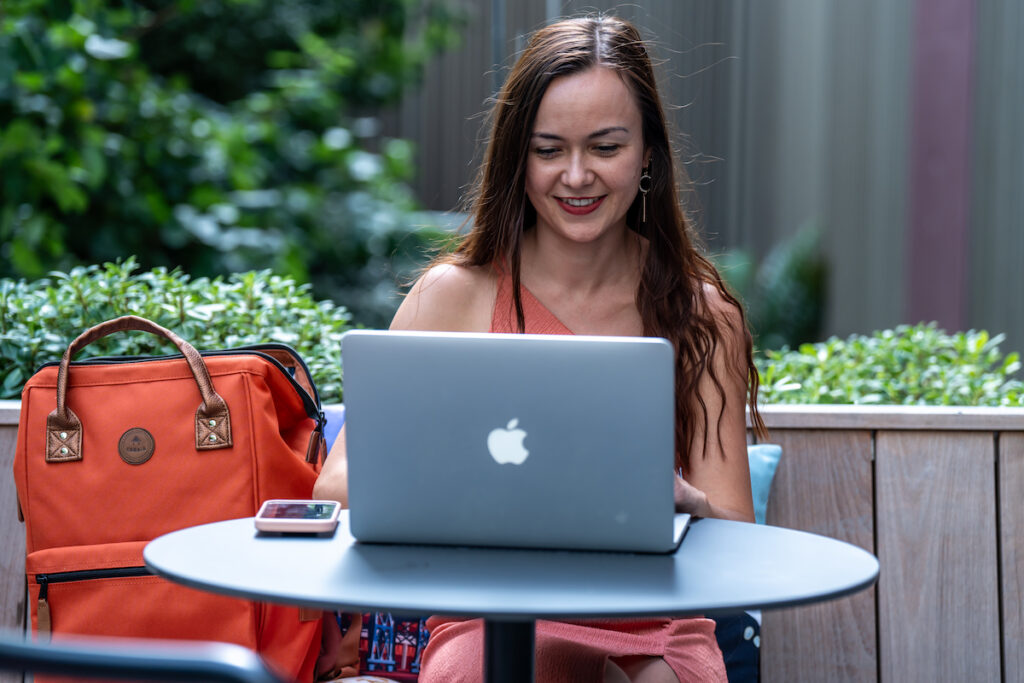 Photo d'Alexia Peytoureau, consultante SEO, derrière un ordinateur sur la terrasse d'un café.