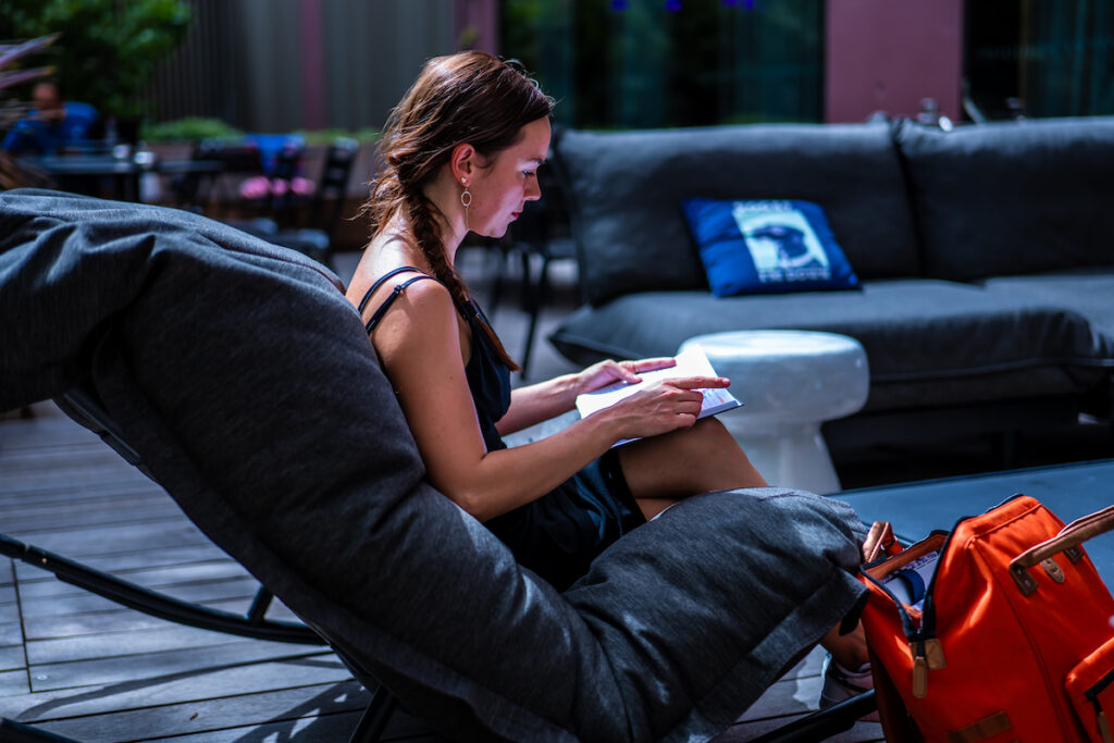 Photo d'Alexia Peytoureau en train de lire sur la terrasse d'un café.