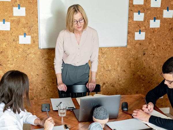 Trois personnes dans une salle, l'une briefe les deux autres sur de la rédaction de contenus pour le web.