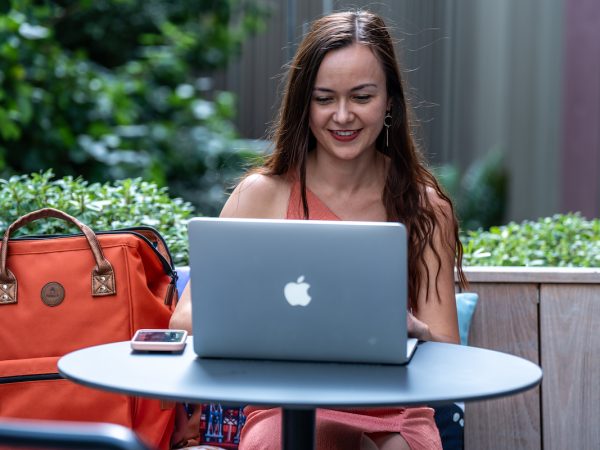 Photo d'Alexia Peytoureau, consultante SEO, derrière un ordinateur sur la terrasse d'un café.